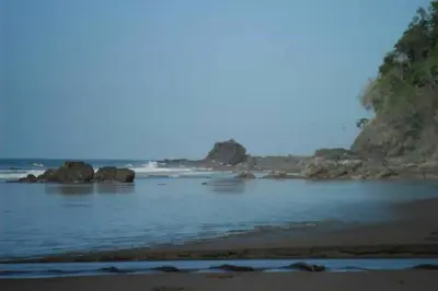 a view of a beach with rocks in the water at Wipeout Guest House in Jacó