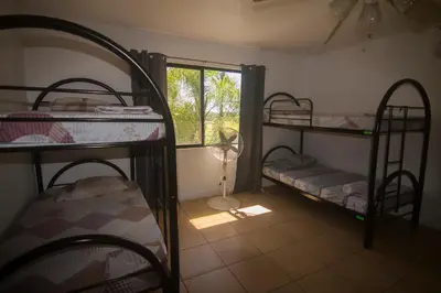 a room with three bunk beds and a window at Wipeout Guest House in Jacó