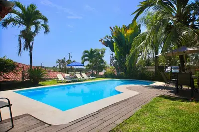 a swimming pool in a yard with palm trees at Wipeout Guest House in Jacó
