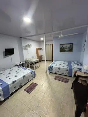 a bedroom with two beds and a desk and a tv at Blue Morpho House B&B in Manuel Antonio