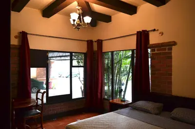 a bedroom with a bed and windows and a chair at Hotel Columbus in San José