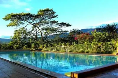 a swimming pool with blue water and trees in the background at Cabinas Lindo Horizonte in San Pedro