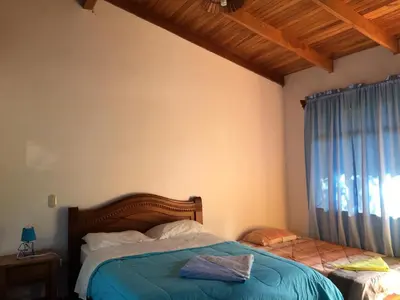 a bedroom with a bed with a blue blanket and a window at Cabinas Lindo Horizonte in San Pedro