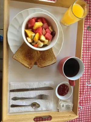 a tray of food with a bowl of fruit and toast at Cabinas Lindo Horizonte in San Pedro