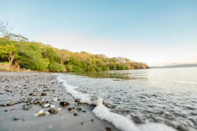 a beach with rocks and a body of water at Papagayo Golden Palms Beachfront Hotel in Papagayo, Guanacaste