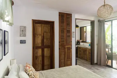 a bedroom with a bed and a door to a kitchen at Ohana Villas in Santa Teresa Beach