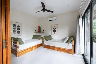 two beds in a room with a window at Ohana Villas in Santa Teresa Beach