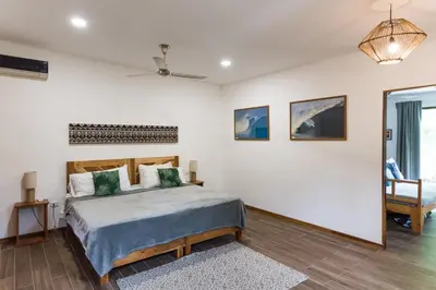 a bedroom with a bed and a table and a chair at Ohana Villas in Santa Teresa Beach