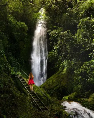a woman walking on a bridge in front of a waterfall at Talamanca Nature Reserve in Rivas