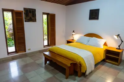 a bedroom with a yellow bed and two windows at Talamanca Nature Reserve in Rivas