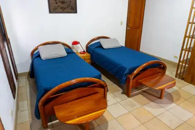 two beds and a chair in a room at Talamanca Nature Reserve in Rivas