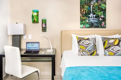 a bedroom with a bed and a desk with a laptop at Tico Tico Villas - Adult Only in Manuel Antonio