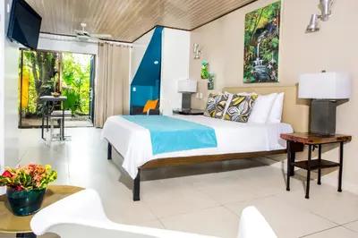 a bedroom with a bed and a table and a tv at Tico Tico Villas - Adult Only in Manuel Antonio