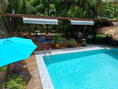 a pool with an umbrella and a table and chairs at CLUB IBIZA - Party Hotel & Beach Club in Jacó