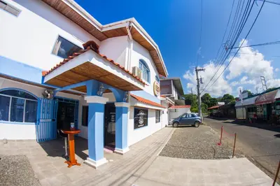 a building with blue columns on a street at CLUB IBIZA - Party Hotel & Beach Club in Jacó
