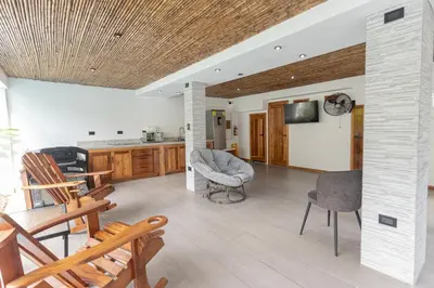 a living room with chairs and a couch and a tv at Inn On The Park in Manuel Antonio