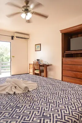 a bedroom with a bed with a ceiling fan and a table at Inn On The Park in Manuel Antonio