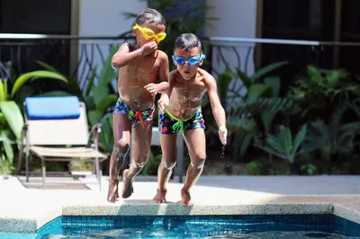 two young boys jumping into a swimming pool at Luxury SKY PENTHOUSES 3-6BR Condo-Hotel at Oceano Jaco in Jacó