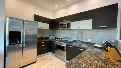 a kitchen with a stainless steel refrigerator and cabinets at Luxury SKY PENTHOUSES 3-6BR Condo-Hotel at Oceano Jaco in Jacó