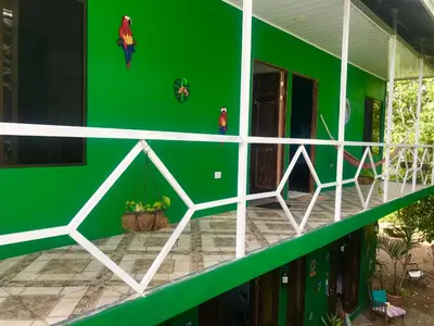 a green wall of a house with a balcony at Guest House Pura Vida in Quepos