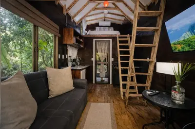 a living room of a tiny house with a couch and ladder at Guest House Pura Vida in Quepos
