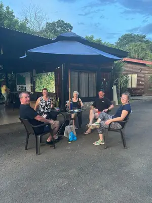 a group of people sitting in chairs under an umbrella at Hotel Pedacito de Cielo in Boca Tapada