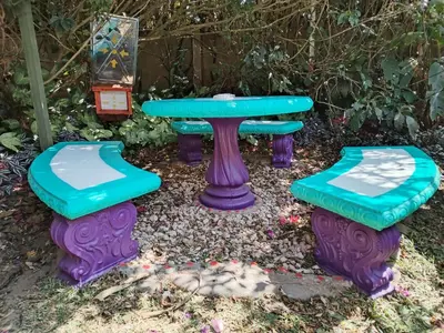 a picnic table and two stools in a garden at Pensión y Cabinas Colibrí B&B Costa Rica in Monteverde Costa Rica