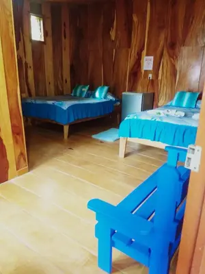 a room with two beds and a chair in it at Pensión y Cabinas Colibrí B&B Costa Rica in Monteverde Costa Rica