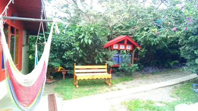 a hammock in front of a house with a garden at Pensión y Cabinas Colibrí B&B Costa Rica in Monteverde Costa Rica