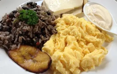 a white plate of food with eggs rice and meat at Pensión y Cabinas Colibrí B&B Costa Rica in Monteverde Costa Rica