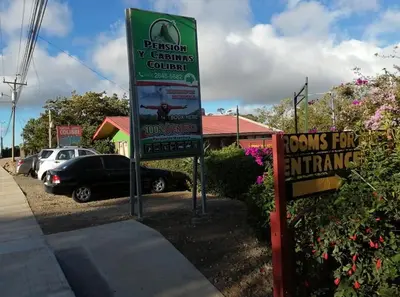 a sign in a parking lot next to a car at Pensión y Cabinas Colibrí B&B Costa Rica in Monteverde Costa Rica