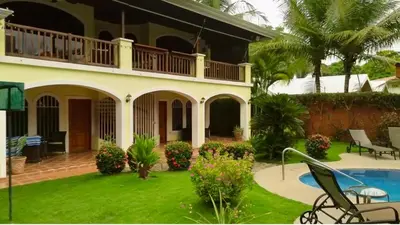 a villa with a swimming pool and a house at Casa Amarilla in Esterillos