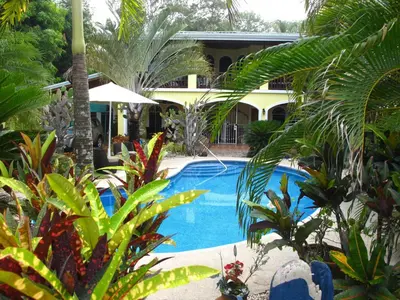 a swimming pool in a garden with trees and plants at Casa Amarilla in Esterillos
