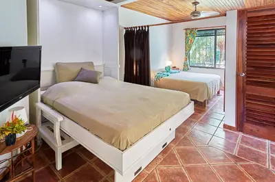 a bedroom with two beds and a flat screen tv at Casa Amarilla in Esterillos