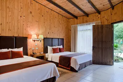 two beds in a room with wooden walls at Savegre Hotel Natural Reserve & Spa in San Gerardo de Dota