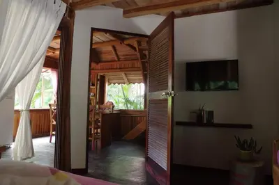 a bedroom with a door open to a room with a television at Griss Lodge & Spa in Santa Teresa Beach