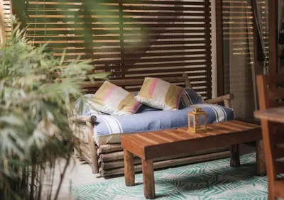 a bed with pillows and a table on a porch at Griss Lodge & Spa in Santa Teresa Beach