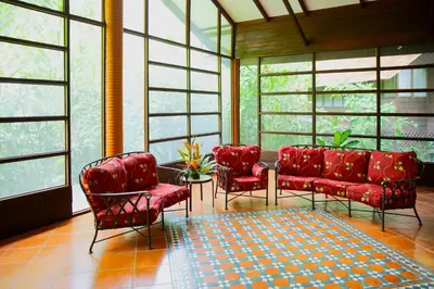 a waiting room with red chairs and windows at Aninga Lodge in Tortuguero