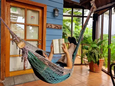 a woman laying in a hammock reading a book at Hotel Claro de Luna in Monteverde Costa Rica