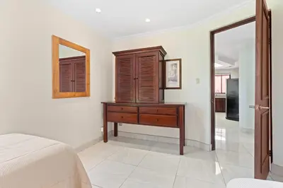 a bedroom with a bed and a dresser and a mirror at Recently Renovated Luxury Condo with Resort-Style Beach Club Access and Ocean Views in Playa Conchal