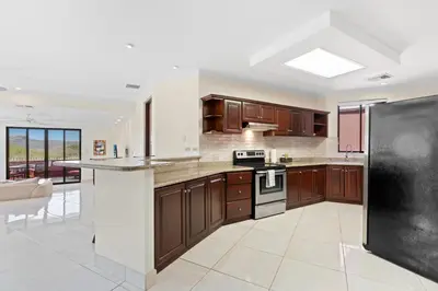 a kitchen with wooden cabinets and a black refrigerator at Recently Renovated Luxury Condo with Resort-Style Beach Club Access and Ocean Views in Playa Conchal