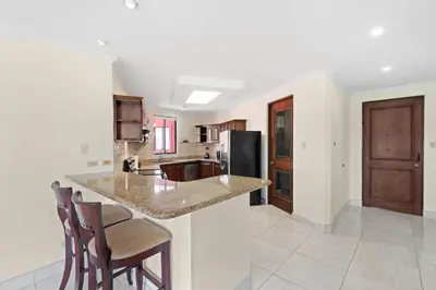 a kitchen with a counter with chairs and a refrigerator at Recently Renovated Luxury Condo with Resort-Style Beach Club Access and Ocean Views in Playa Conchal