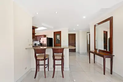 a kitchen with a bar with stools and a mirror at Recently Renovated Luxury Condo with Resort-Style Beach Club Access and Ocean Views in Playa Conchal