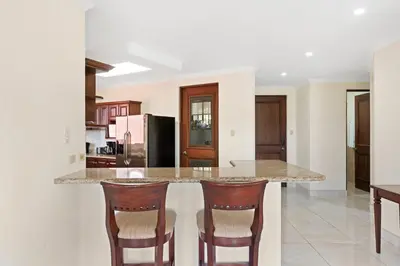 a kitchen with a counter and two bar stools at Recently Renovated Luxury Condo with Resort-Style Beach Club Access and Ocean Views in Playa Conchal