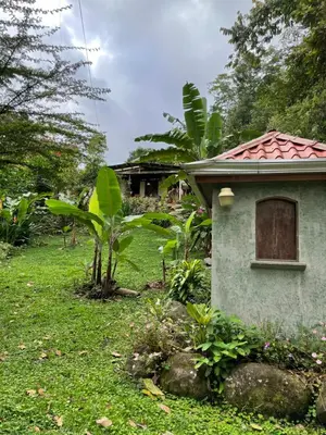 a small building with a window in the grass at Finca Isla Rainforest Retreat in Aguas Zarcas