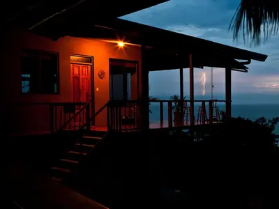 a house with a red door and a view of the ocean at Santa Teresa Surf Vista Villas in Santa Teresa Beach