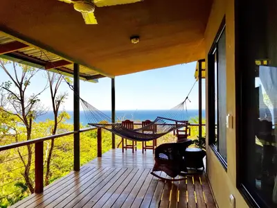 a porch with a hammock and a view of the ocean at Santa Teresa Surf Vista Villas in Santa Teresa Beach