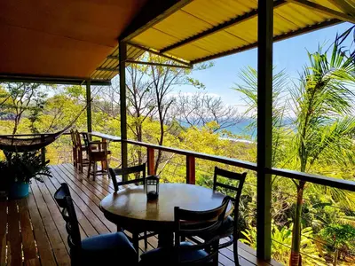 a wooden deck with a table and chairs on it at Santa Teresa Surf Vista Villas in Santa Teresa Beach