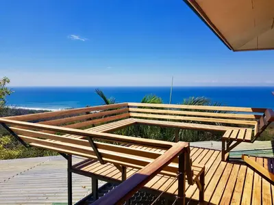 a bench on a deck with the ocean in the background at Santa Teresa Surf Vista Villas in Santa Teresa Beach