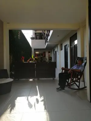 a man sitting in a rocking chair in a living room at Cabinas Gosen in Puntarenas